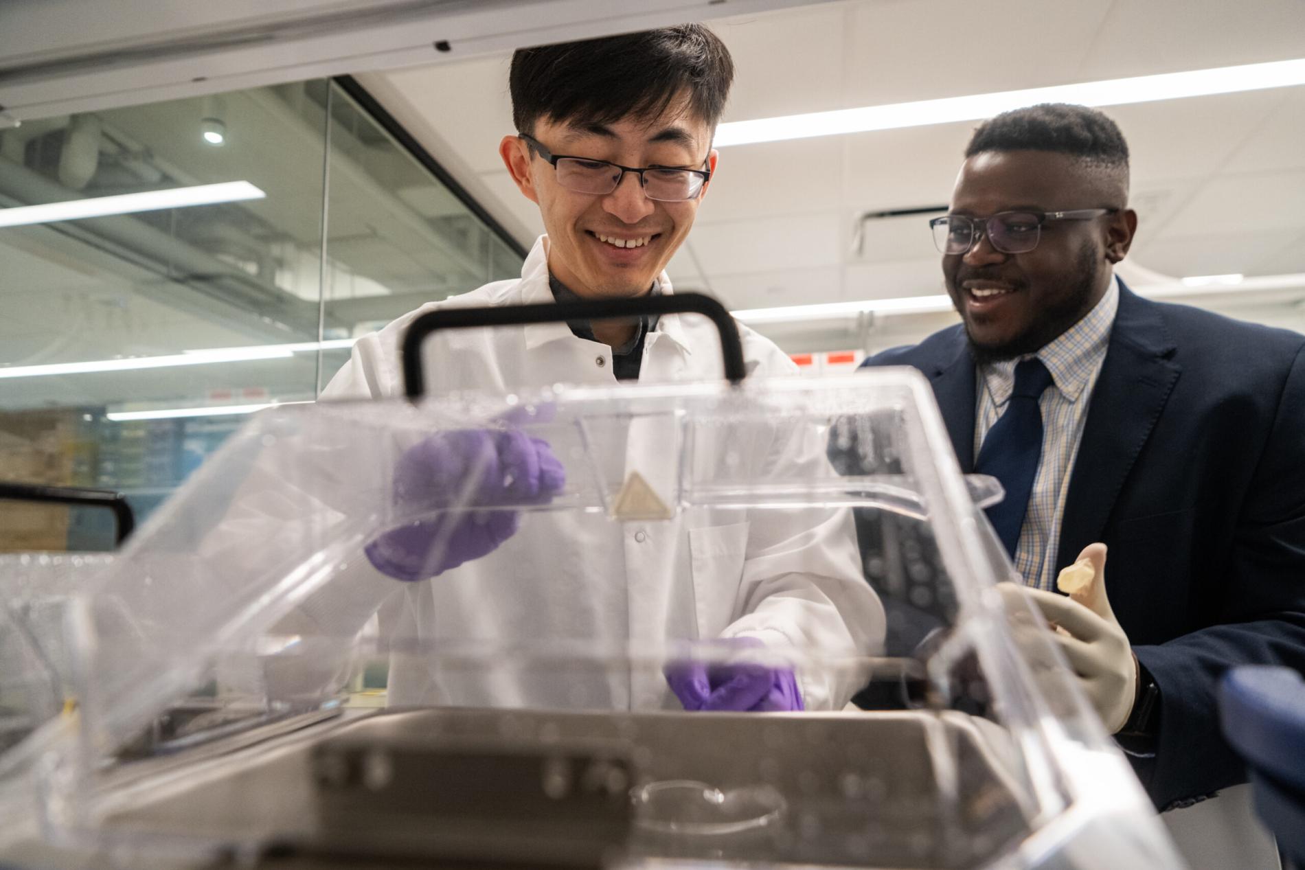 Two students work on equipment in lab
