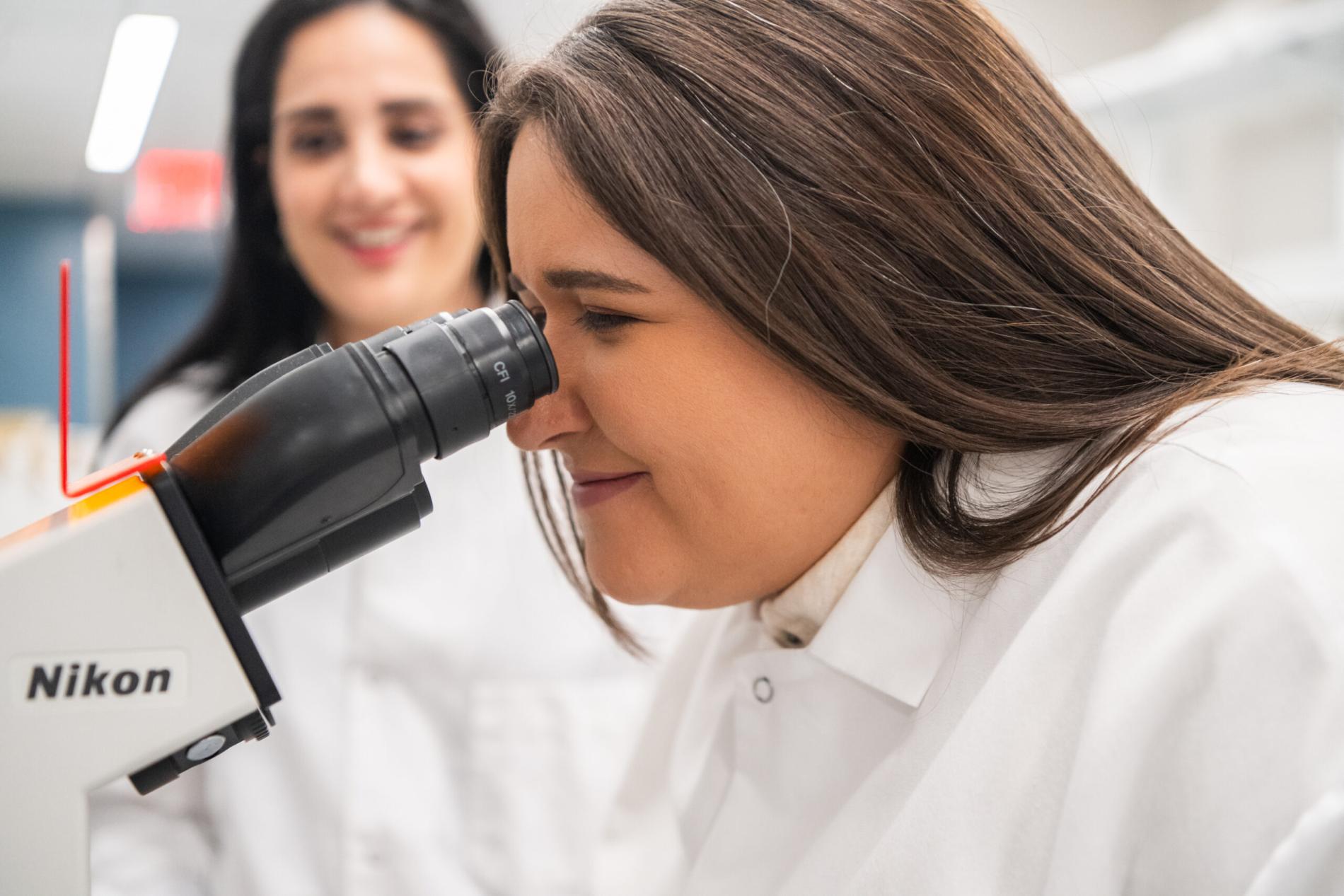 Female researcher looks through a microscope